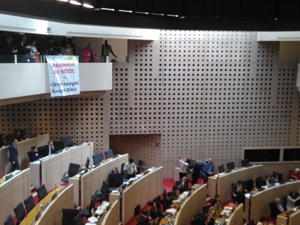 Déploiement d'une banderole et lancer d'avions en papier dans l'assemblée du Conseil régional