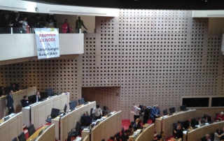 Déploiement d'une banderole et lancer d'avions en papier dans l'assemblée du Conseil régional