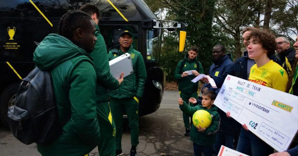 billet de train géant porté par des militants climat aux joueurs et à l'entraîneur du FC Nantes, devant leur bus