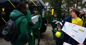 billet de train géant porté par des militants climat aux joueurs et à l'entraîneur du FC Nantes, devant leur bus