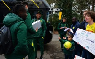 billet de train géant porté par des militants climat aux joueurs et à l'entraîneur du FC Nantes, devant leur bus